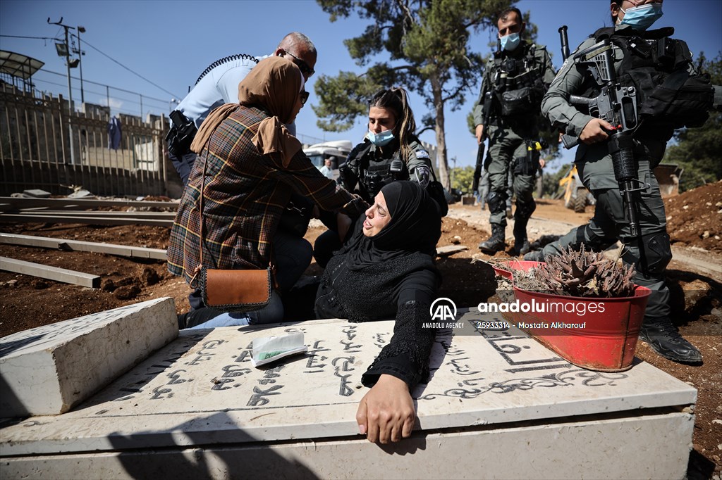 Palestinian mother reacts on her son's grave to Israel's works to turn part of cemetery into a park