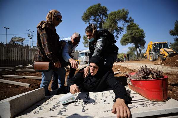 Palestinian mother reacts on her son's grave to Israel's works to turn part of cemetery into a park