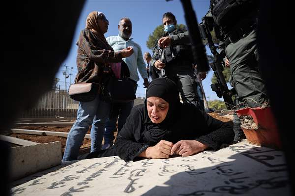 Palestinian mother reacts on her son's grave to Israel's works to turn part of cemetery into a park