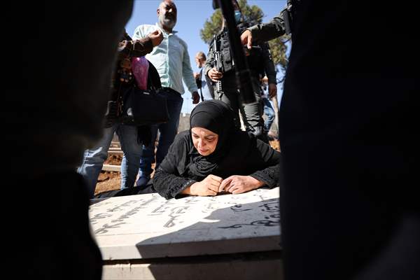 Palestinian mother reacts on her son's grave to Israel's works to turn part of cemetery into a park