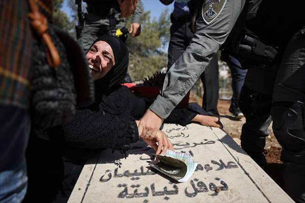 Palestinian mother reacts on her son's grave to Israel's works to turn part of cemetery into a park