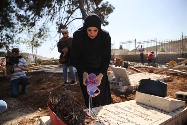 Palestinian mother reacts on her son's grave to Israel's works to turn part of cemetery into a park