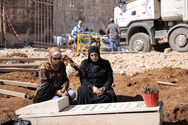 Palestinian mother reacts on her son's grave to Israel's works to turn part of cemetery into a park