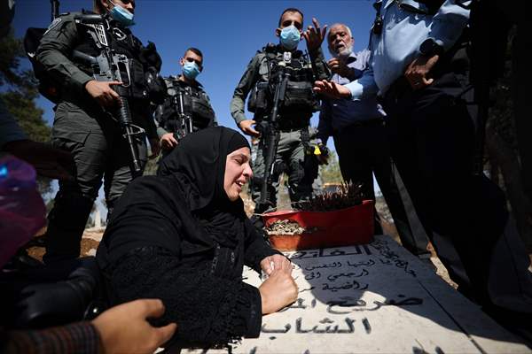 Palestinian mother reacts on her son's grave to Israel's works to turn part of cemetery into a park