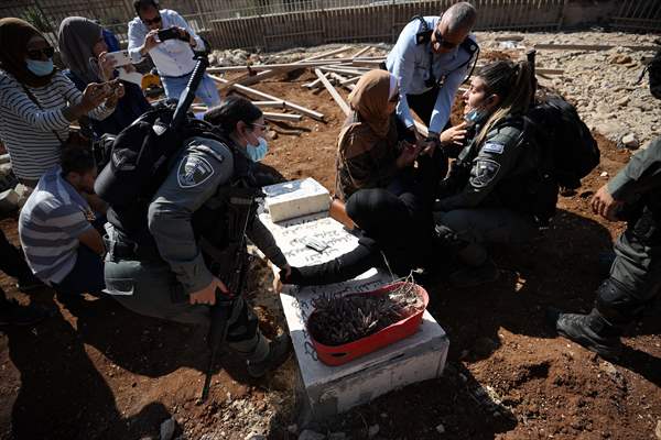 Palestinian mother reacts on her son's grave to Israel's works to turn part of cemetery into a park