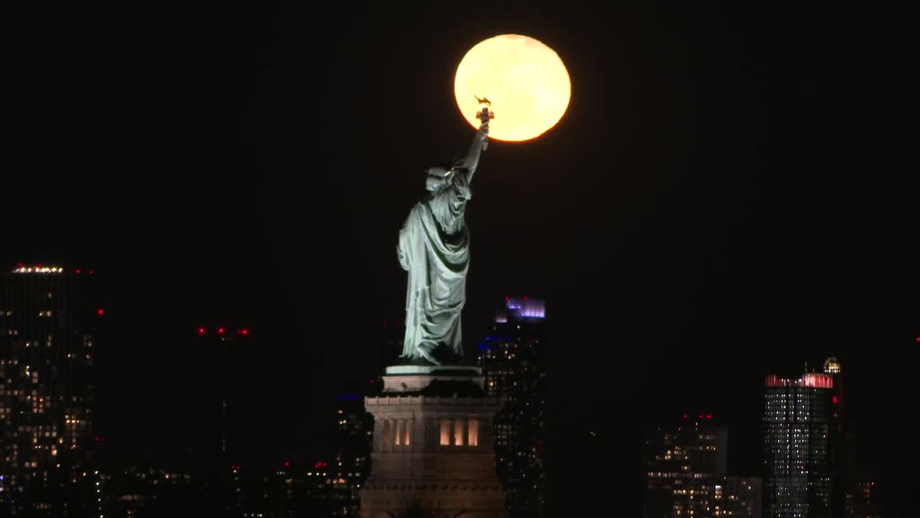 Full Moon rises behind Statue of Liberty in New York City