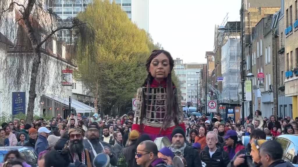 Giant puppet depicting Syrian refugee girl walk streets of London